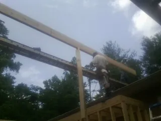 Carpenter setting a ridge beam over a new addition frame — Ice Dam Removal by Roofing Brothers in Spencer